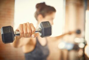 6 strength training benefits everyone should know about woman lifting weights at gym dumbbells